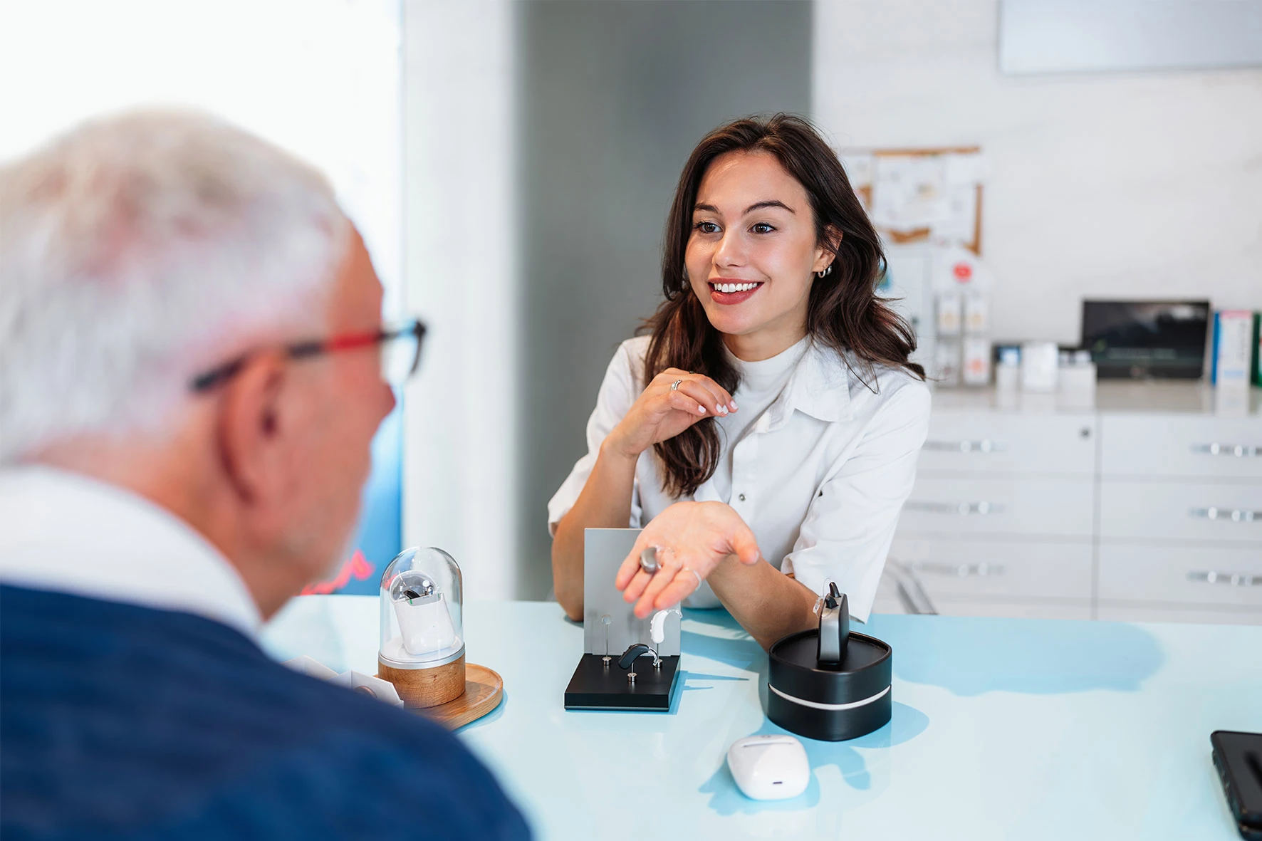 Hörakustikerin berät älteren Kunden zu Hörgerät im Fachgeschäft.